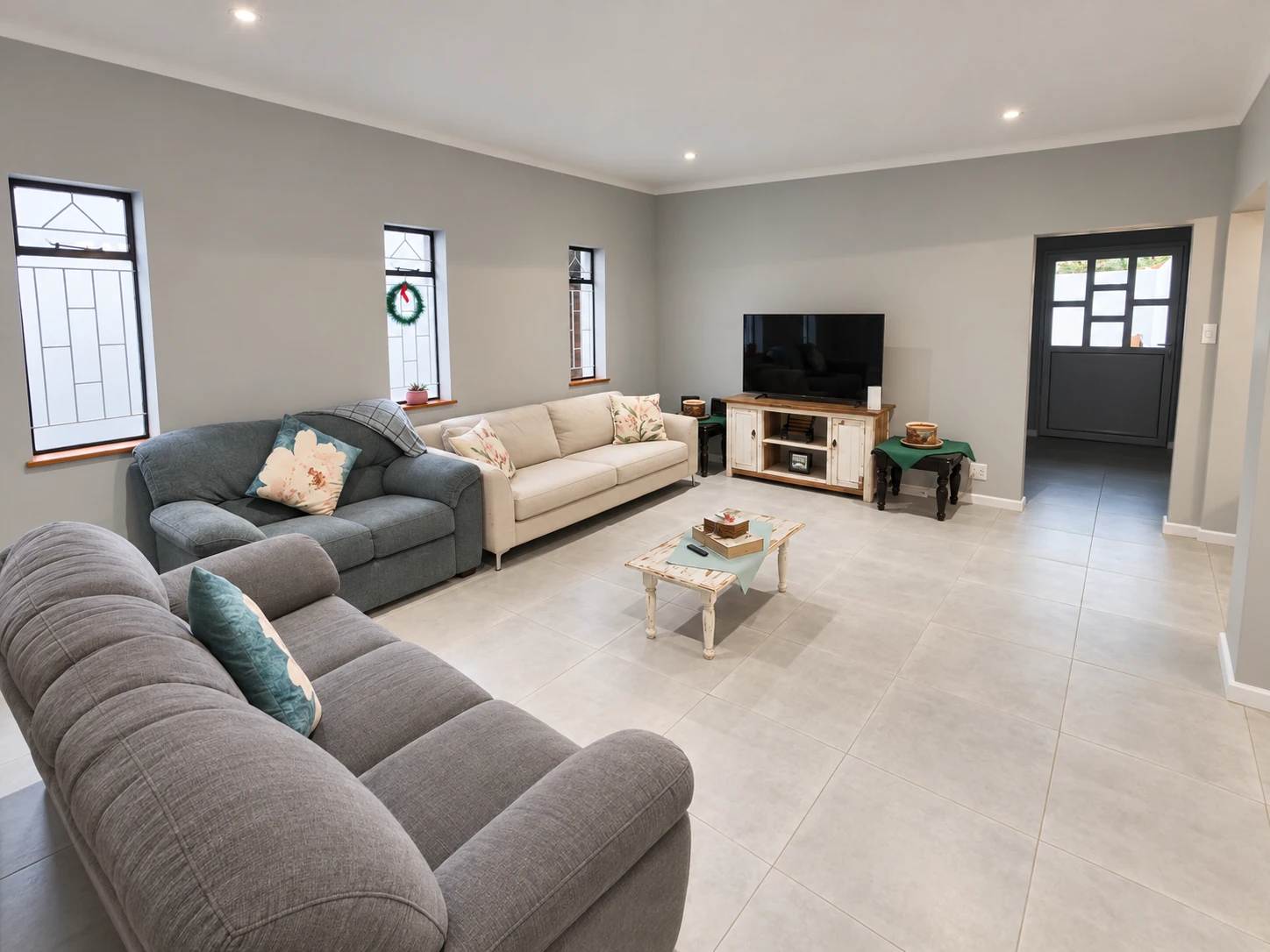 El Shaddai lounge with three sofas, a coffee table and television; upholstery colours retouched